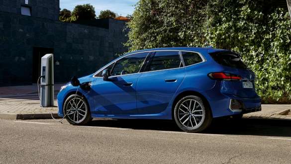 BMW Serie 2 Active Tourer 230e Híbrido Enchufable U06 2021 aparcado en un punto de carga BMW Serie 2 Active Tourer 230e Híbrido Enchufable U06 2021 M Portimao Blue metalizado, vista lateral, aparcado en un punto de carga