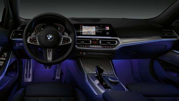 BMW Serie 3 (G20), luz ambiente. Toma frontal del lado del conductor del puesto de conducción del BMW Serie 3 (G20), con el espacio para los pies iluminado en azul mediante la luz ambiente.