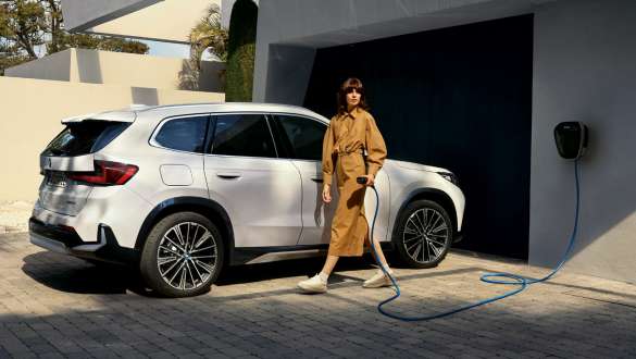 BMW iX1 U11 BEV 2022 Entrada del garaje BMW iX1 U11 BEV 2022 Mineral White metalizado Vista lateral de ¾ Aparcado en la entrada del garaje