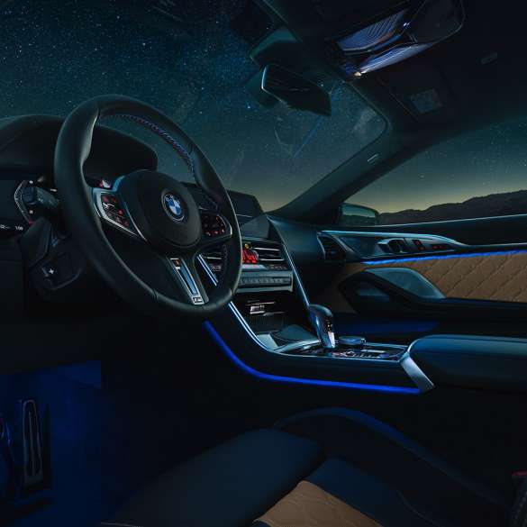 BMW M8 Competition Coupé, puesto de conducción. BMW M8 Competition Coupé, puesto de conducción de noche con volante M de cuero y luz ambiente azul.