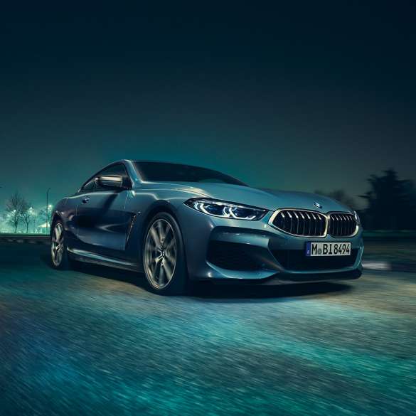 BMW M850i xDrive Coupé, vista de tres cuartos del frontal desde la izquierda. BMW M850i xDrive Coupé en Barcelona Blau metalizado, vista de tres cuartos del frontal desde la izquierda, en marcha, por la noche.