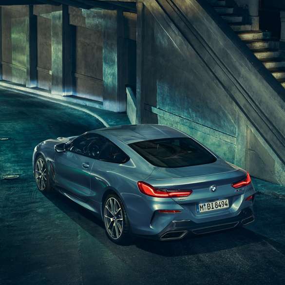 BMW M850i xDrive Coupé, vista de tres cuartos de la zaga desde la izquierda. BMW M850i xDrive Coupé en Barcelona Blau metalizado, vista de tres cuartos de la zaga desde la izquierda, parado, por la noche.