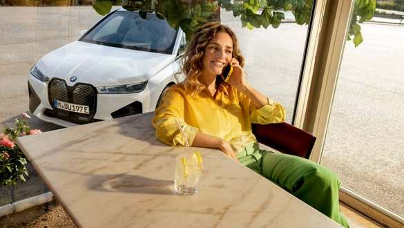 Neumáticos BMW, mujer delante de un BMW X5 en un ambiente brumoso Neumáticos BMW, mujer delante de un BMW X5 en un ambiente brumoso