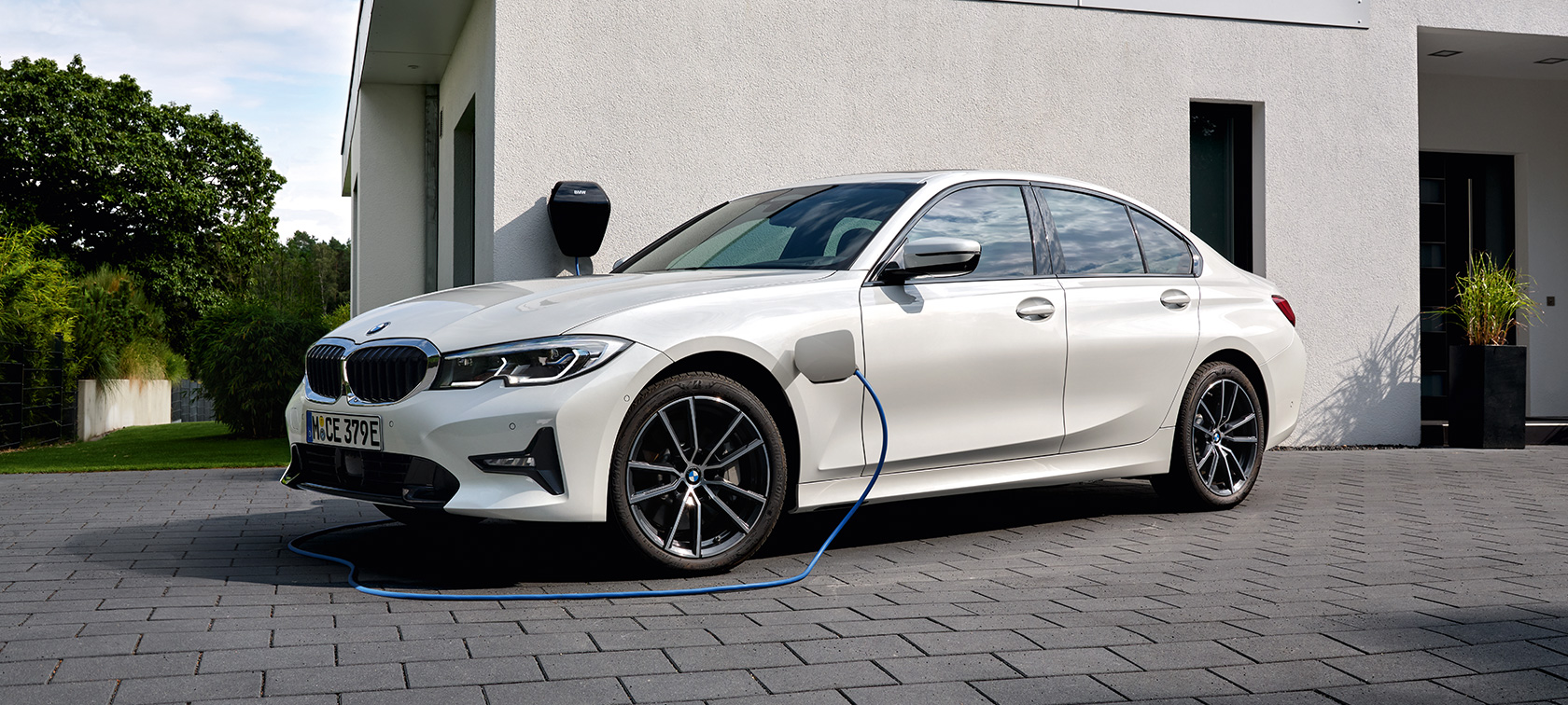 BMW Serie 3 Híbrido Enchufable 2021 G20, vista de tres cuartos del lateral, carga BMW Serie 3 Híbrido Enchufable 2021 G20, vista de tres cuartos del lateral, carga delante de un garaje