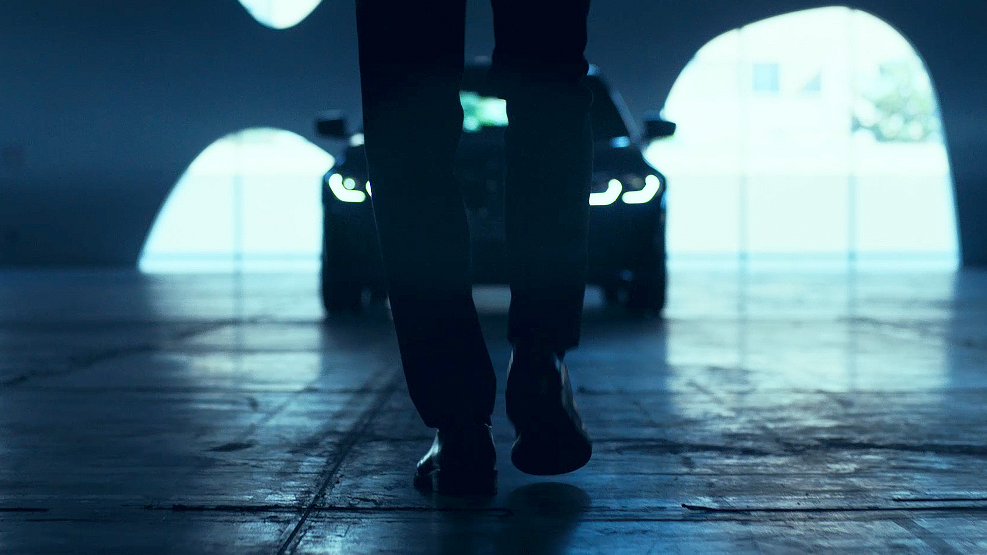 Vista desde atrás de un peatón delante del BMW Serie 3 sobre el asfalto.