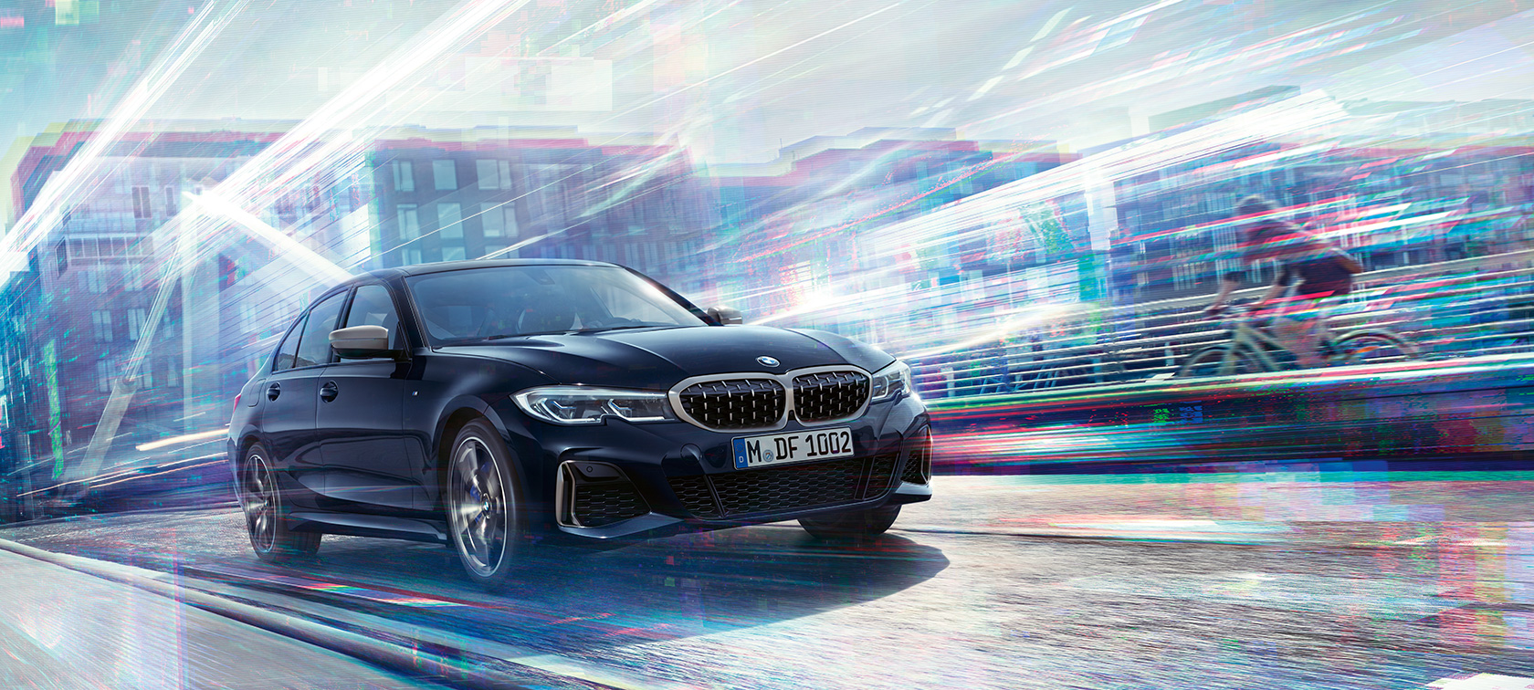 BMW Serie 3 Berlina, BMW M340i xDrive. Vista lateral de tres cuartos del BMW M340i xDrive por la carretera con la ciudad de fondo.
