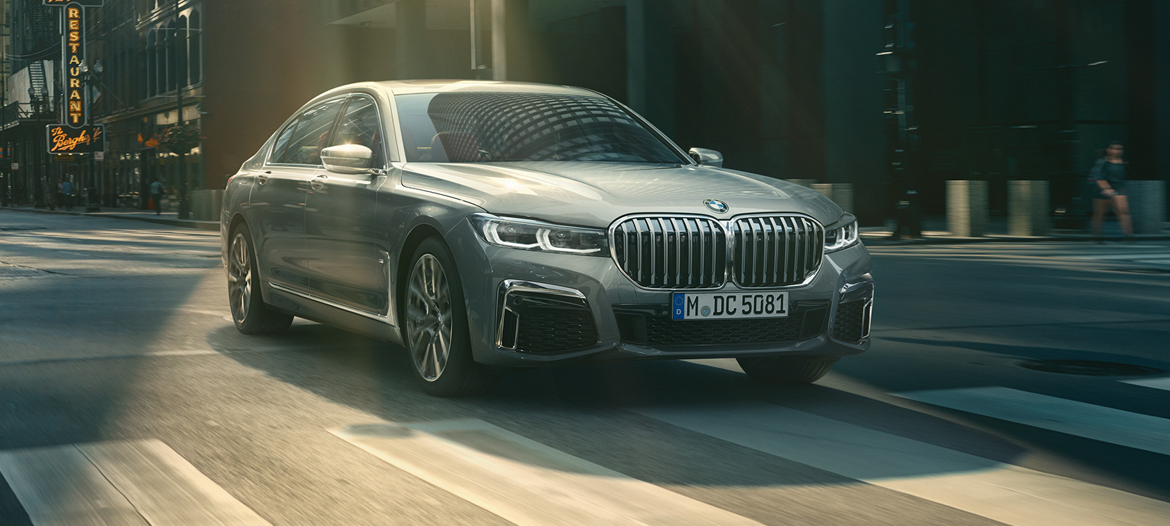 BMW Serie 7 gris en marcha, vista de tres cuartos del frontal BMW Serie 7 gris, en una vista de tres cuartos del frontal, que circula por un entorno urbano