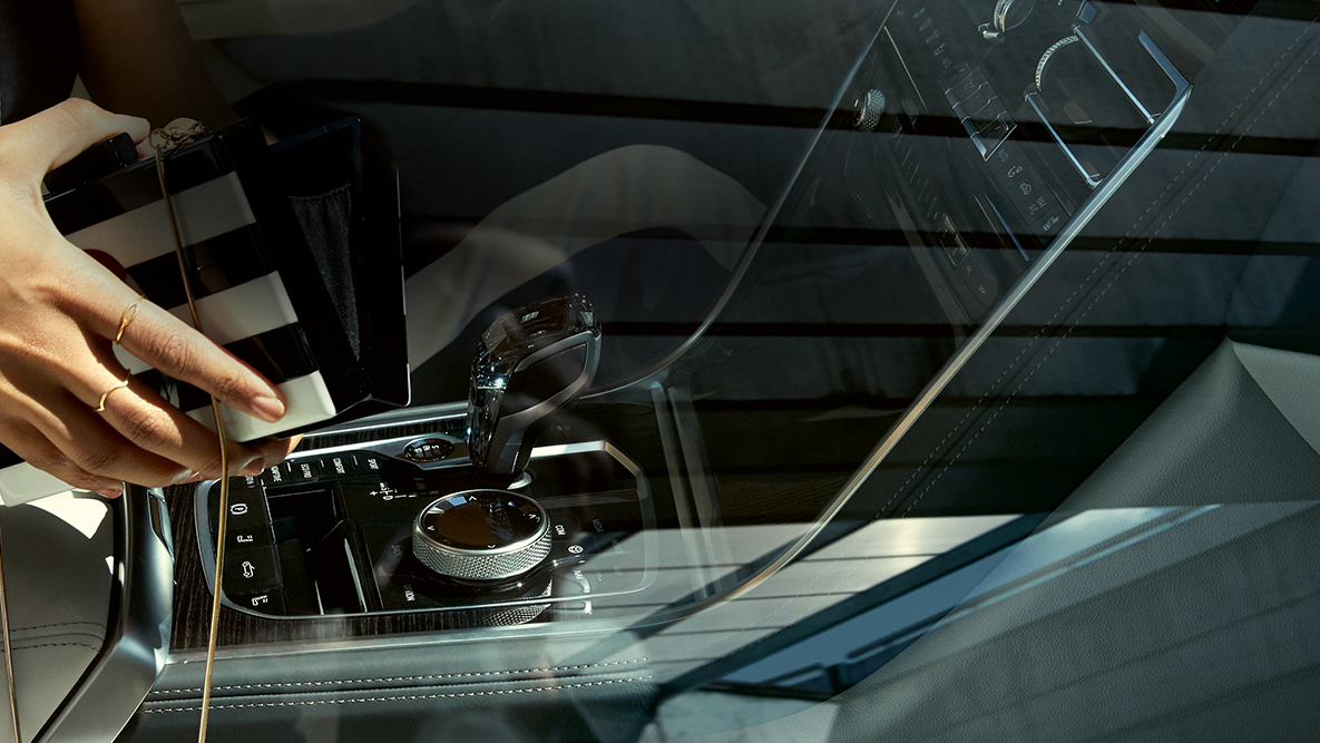 Interior del BMW M850i xDrive, con aplique de cristal CraftedClarity, y mujer con bolso abierto. Interior del BMW M850i xDrive, con aplique de cristal CraftedClarity, y mujer con bolso abierto.