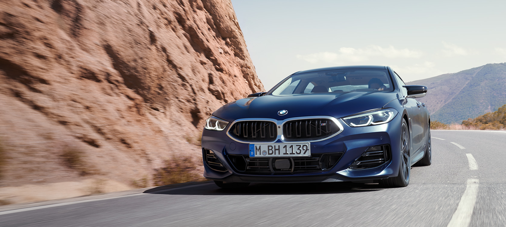 BMW Serie 8 Gran Coupé G16 LCI Renovación 2022 BMW Individual Frozen Tanzanite Blue metalizado, vista de tres cuartos del frontal, circulando por una carretera de montaña