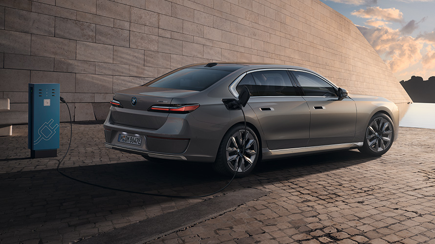 BMW i7 G70 Vista de 3/4 de la zaga BMW i7 G70 BMW Individual Oxide Grey metalizado, vista de 3/4 de la zaga, parado delante de un edificio