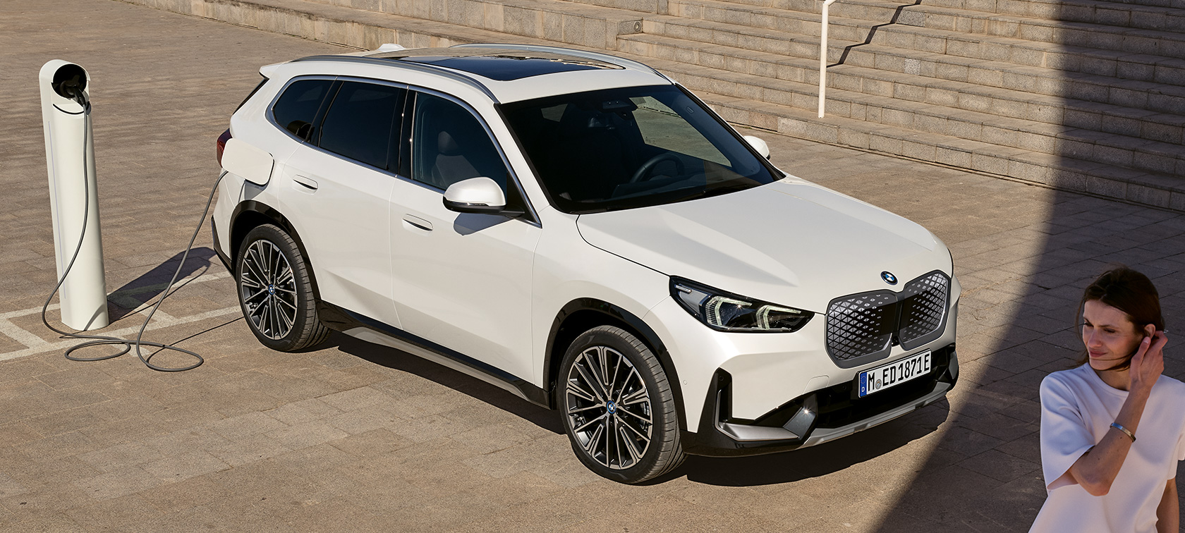 BMW iX1 U11 BEV vista del lateral, cargando BMW iX1 U11 BEV 2022 Mineral White metalizado, vista de dos tercios del lateral, cargando, escalera