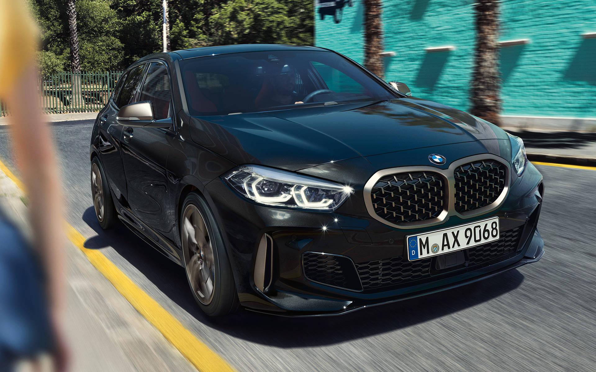 BMW M135i xDrive (F40) en Black Sapphire metalizado, vista de tres cuartos del frontal, en marcha