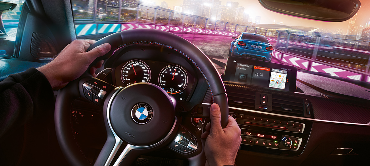 El puesto de conducción del BMW M2 Competition Dos vehículos BMW M2 Competition en competición por la noche en una vista desde el puesto de conducción.