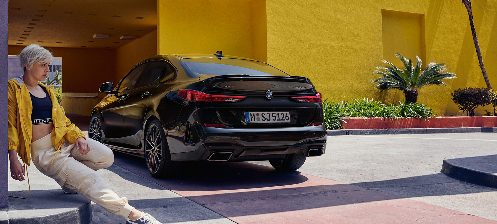 Nuevo BMW M235i xDrive Gran Coupé, vista de tres cuartos de la zaga F44 Nuevo BMW M235i xDrive Gran Coupé Black Sapphire metalizado F44, vista de tres cuartos de la zaga con mujer delante