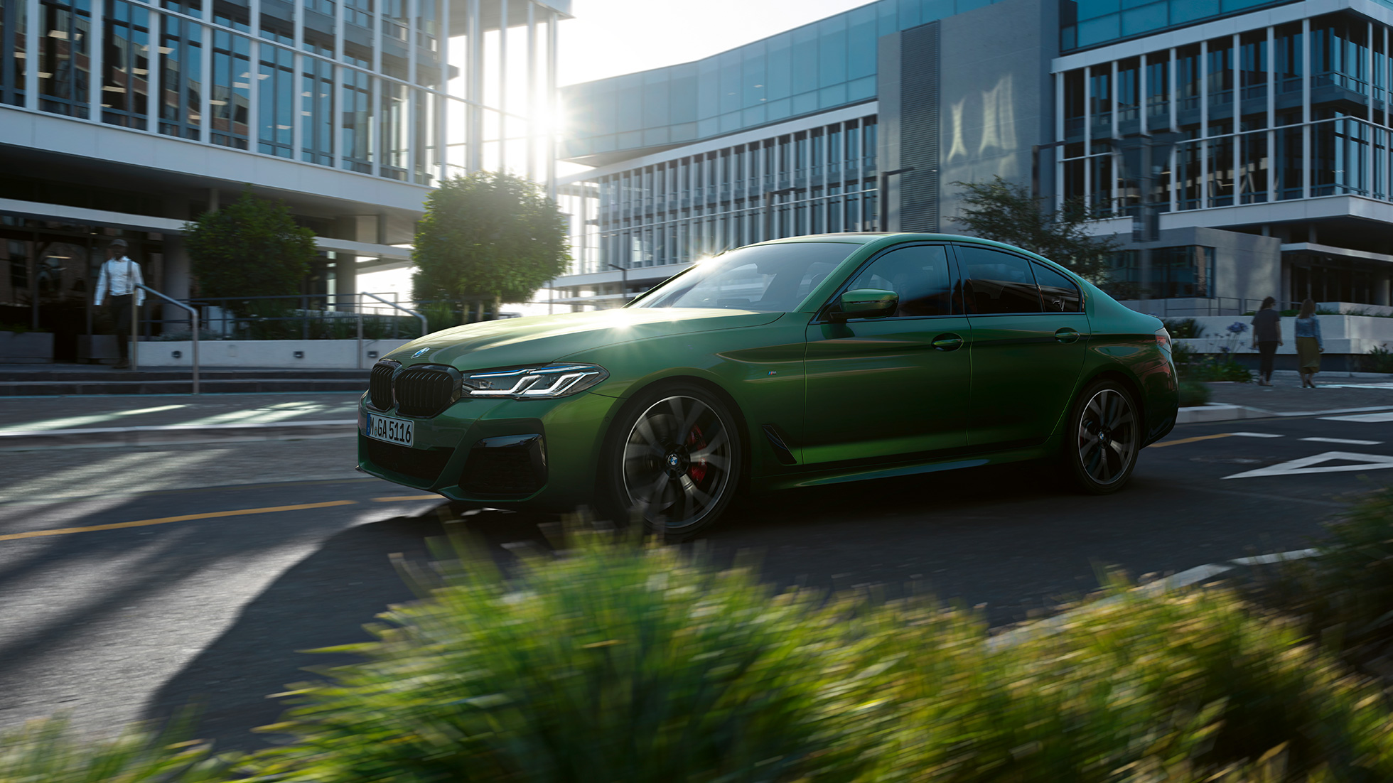 BMW M550i xDrive Berlina G30 LCI Renovación 2020 Vista lateral en marcha BMW M550i xDrive Berlina G30 LCI Renovación 2020 BMW Individual Verde Ermes metalizado Vista lateral en marcha en la ciudad