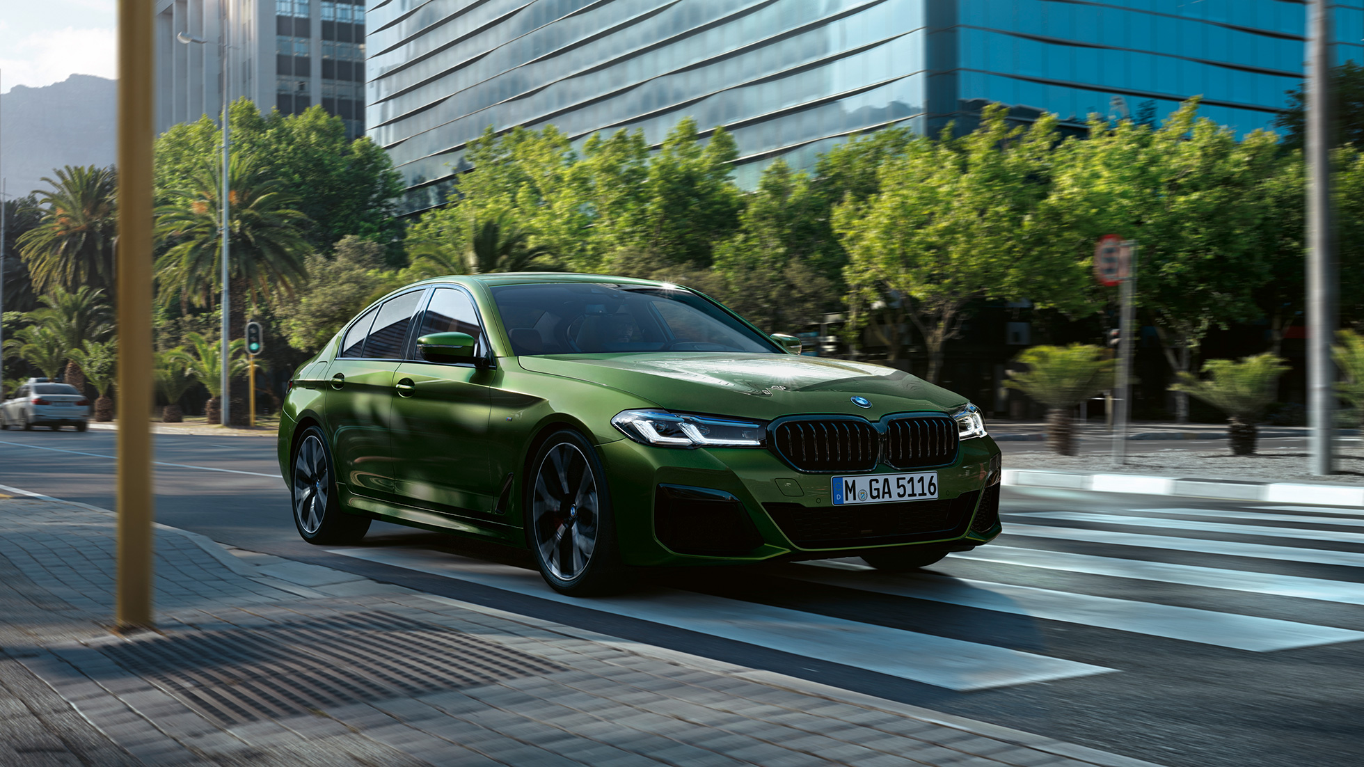 BMW M550i xDrive Berlina G30 LCI Renovación 2020 Vista de tres cuartos del frontal en marcha BMW M550i xDrive Berlina G30 LCI Renovación 2020 BMW Individual Verde Ermes metalizado Vista de tres cuartos del frontal en marcha en la ciudad