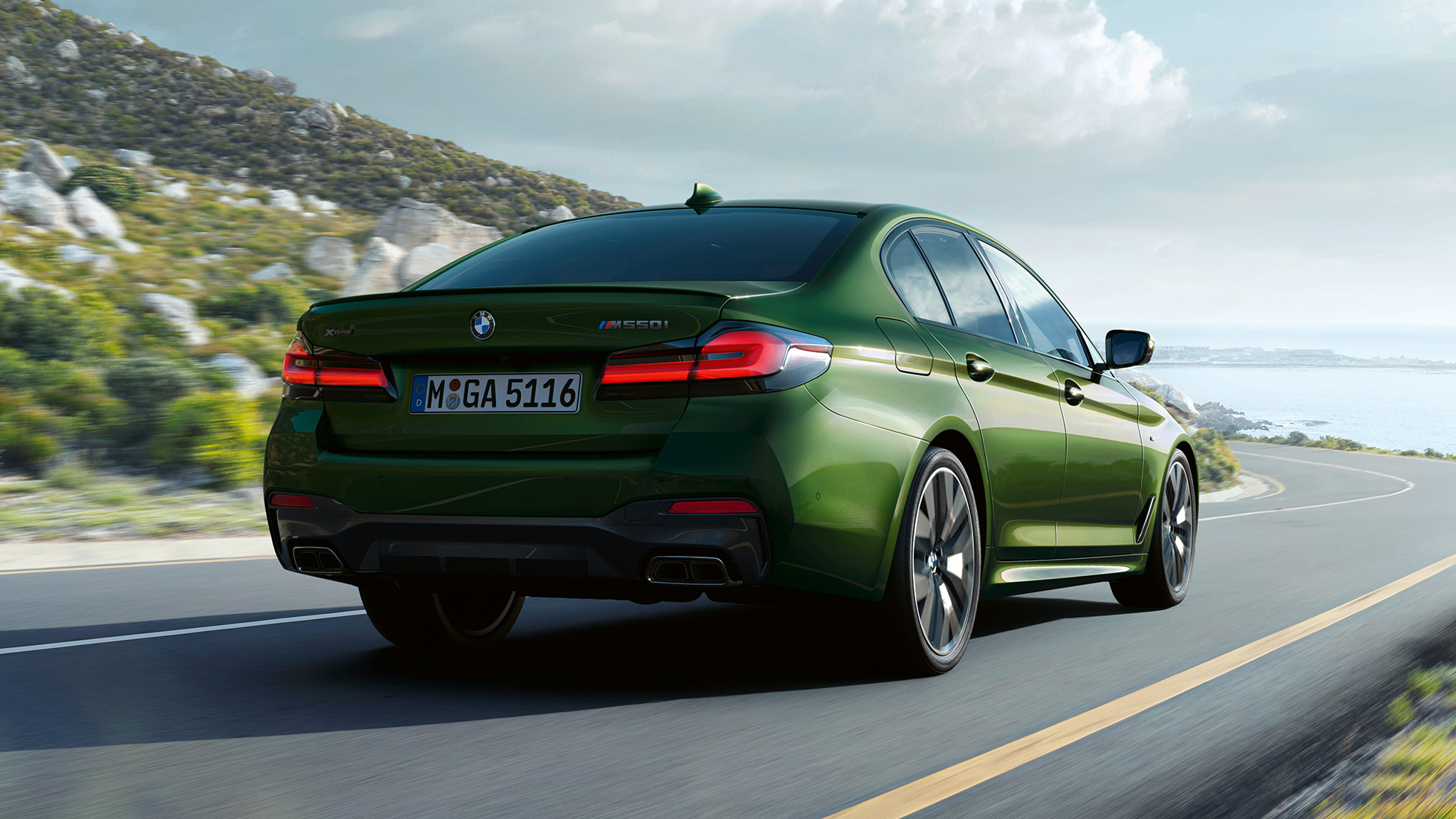 BMW M550i xDrive Berlina G30 LCI Renovación 2020 Vista de la zaga BMW M550i xDrive Berlina G30 LCI Renovación 2020 BMW Individual Verde Ermes metalizado Vista de la zaga en marcha por una carretera