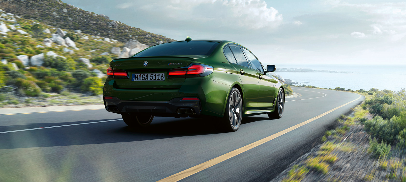 BMW M550i xDrive Berlina G30 LCI Renovación 2020 Vista de tres cuartos de la zaga en marcha BMW M550i xDrive Berlina G30 LCI Renovación 2020 BMW Individual Verde Ermes metalizado Vista de tres cuartos de la zaga en marcha