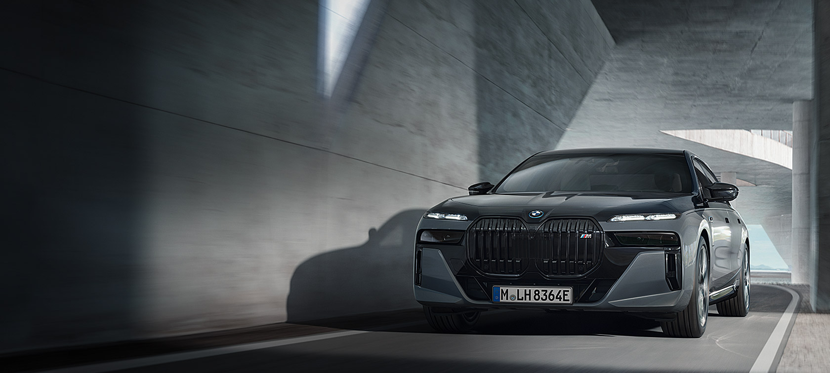 BMW M760e xDrive Berlina G70 Paquete M Performance, pintura bicolor BMW Individual Black Sapphire metalizado BMW Individual Dravit Grey metalizado, vista de tres cuartos del frontal, en marcha por la carretera