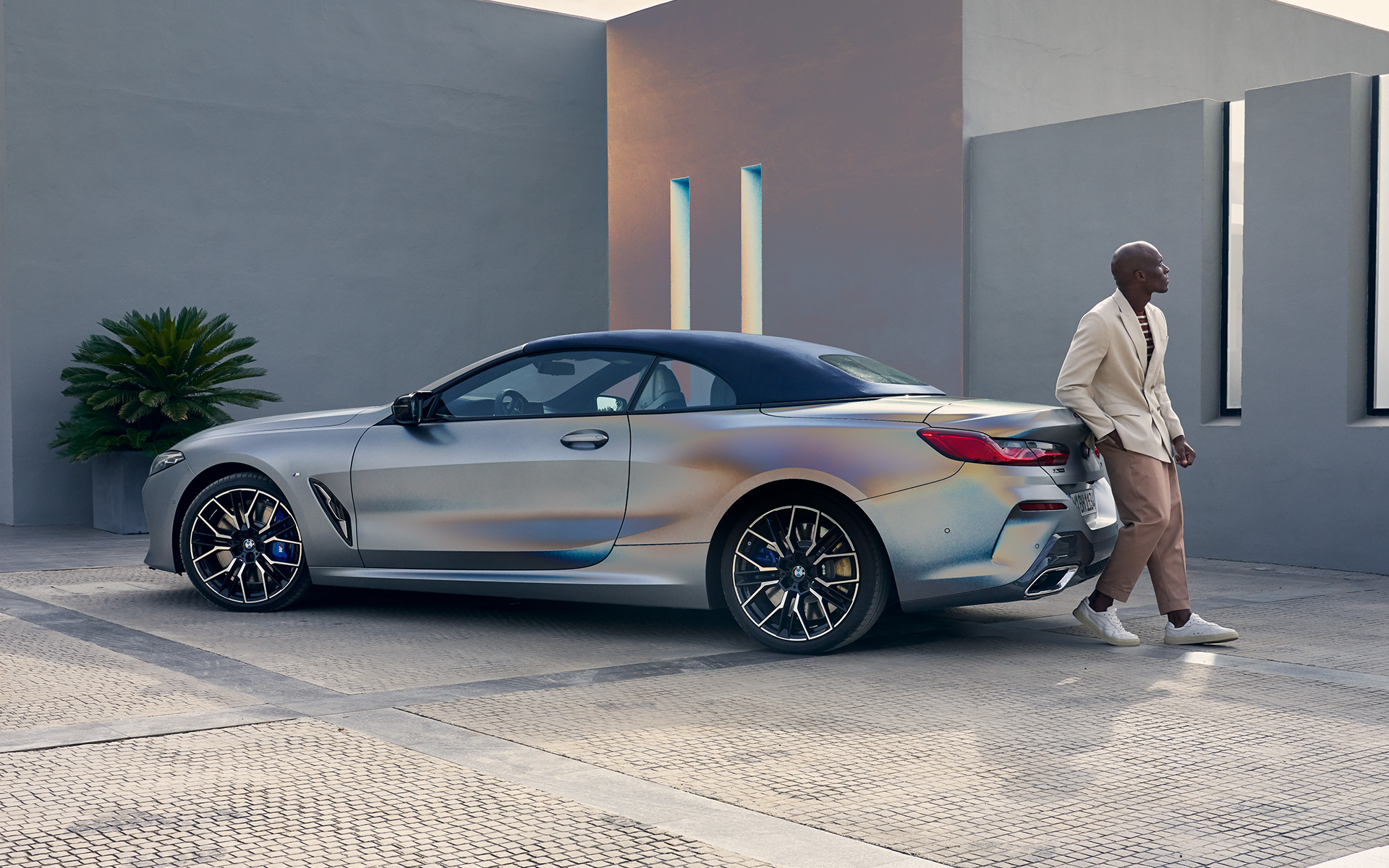 BMW M850i xDrive Cabrio G14 LCI Renovación 2022 BMW Individual Frozen Pure Grey metalizado, vista de tres cuartos de la zaga, con modelo masculino apoyado en un vehículo