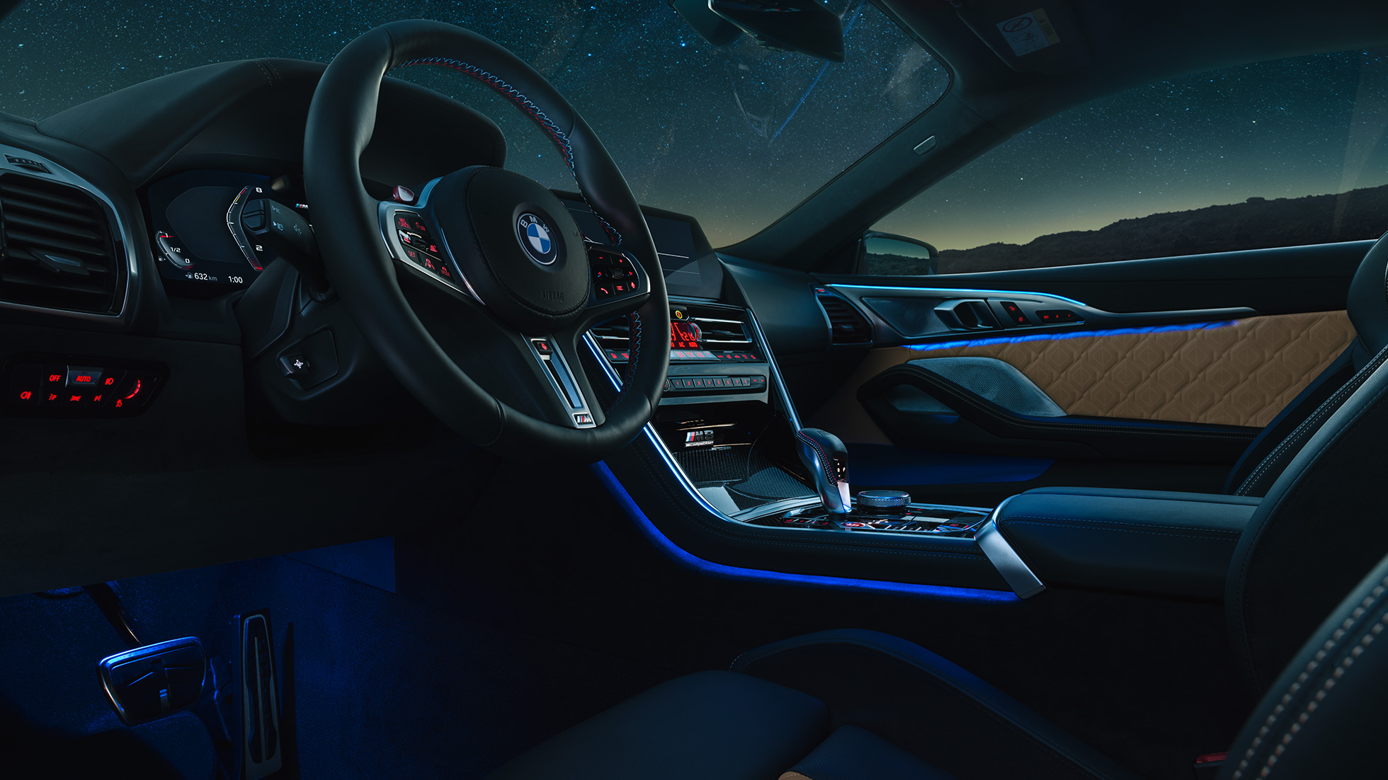 BMW M8 Competition Coupé, puesto de conducción. BMW M8 Competition Coupé, puesto de conducción de noche con volante M de cuero y luz ambiente azul.