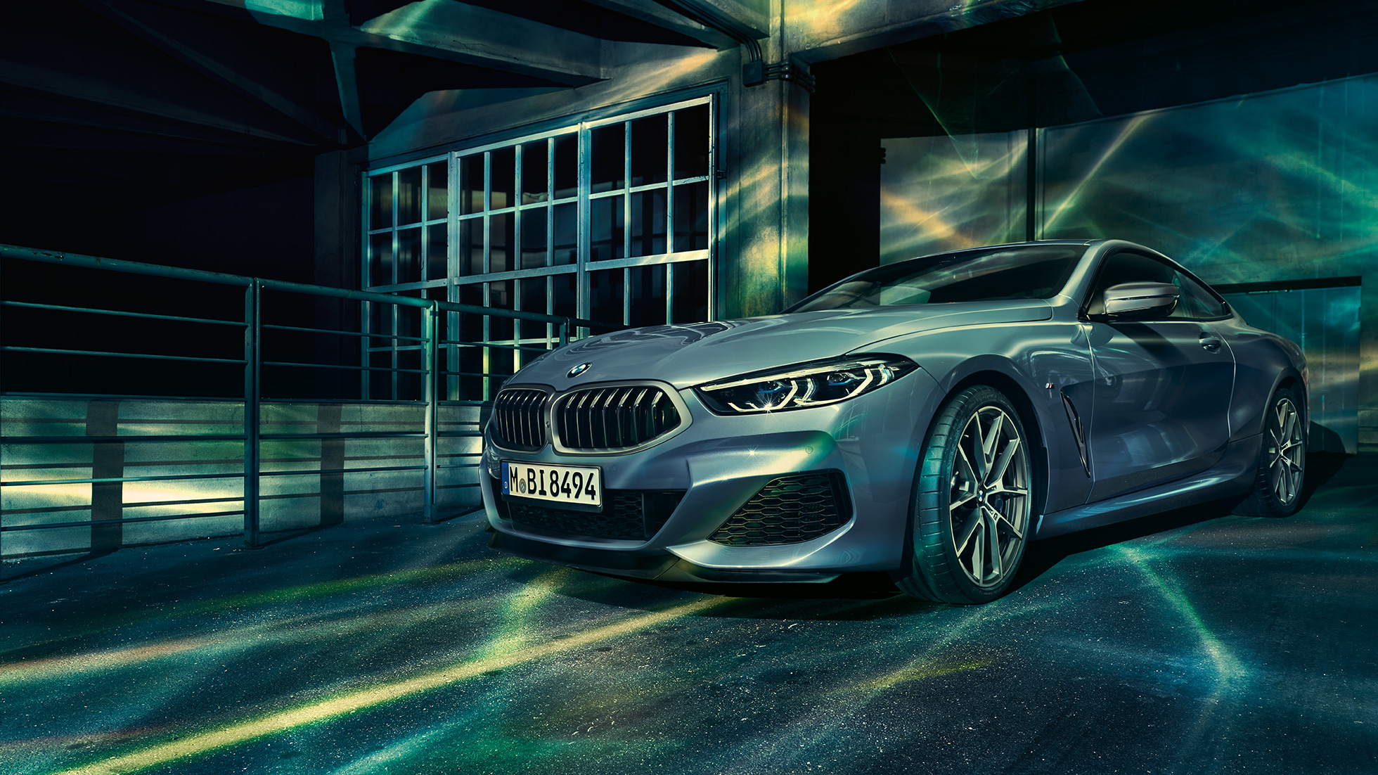 BMW M850i xDrive Coupé, vista de tres cuartos del frontal. BMW M850i xDrive Coupé en Barcelona Blau metalizado, vista de tres cuartos del frontal, parado delante de un edificio.