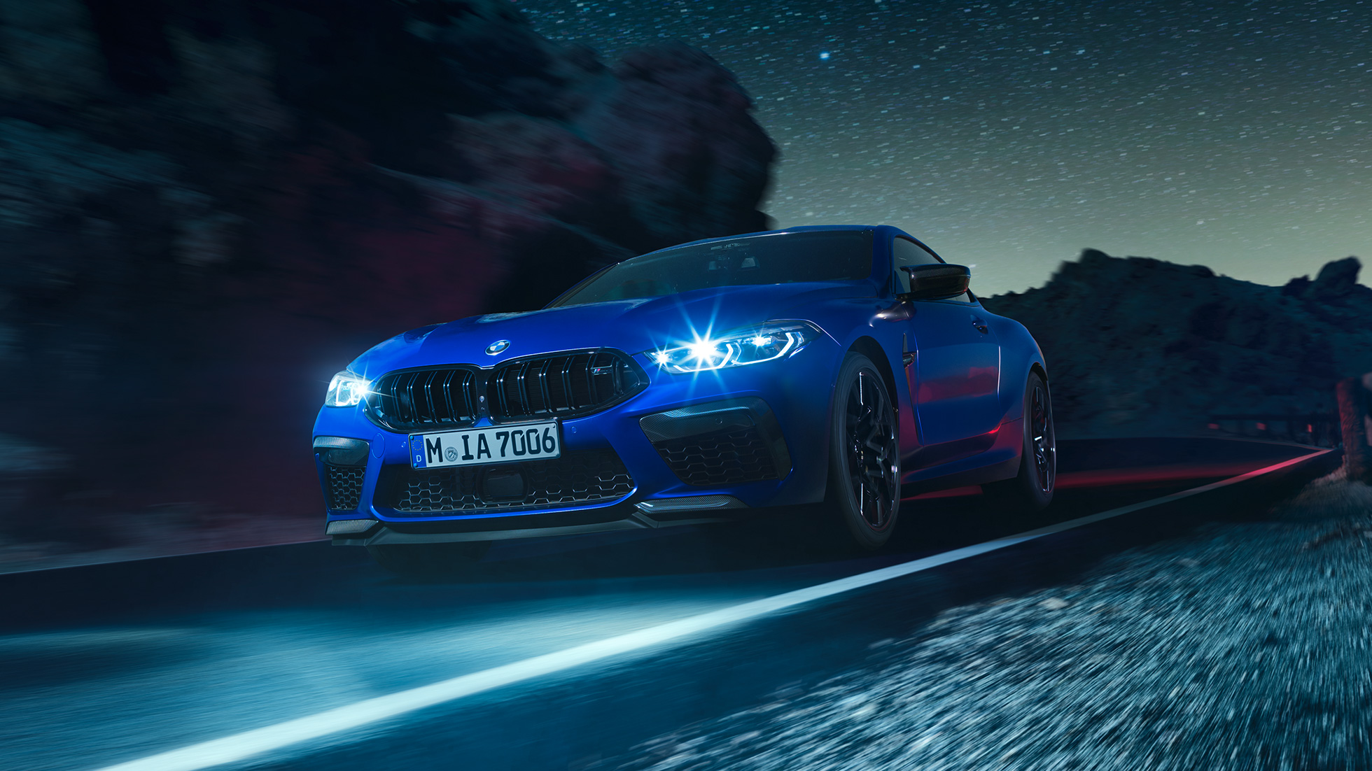 BMW M8 Competition Coupé, vista de tres cuartos del frontal. BMW M8 Competition Coupé en Marina Bay Blau metalizado con los faros LED encendidos, vista de tres cuartos del frontal, en marcha, por la noche.