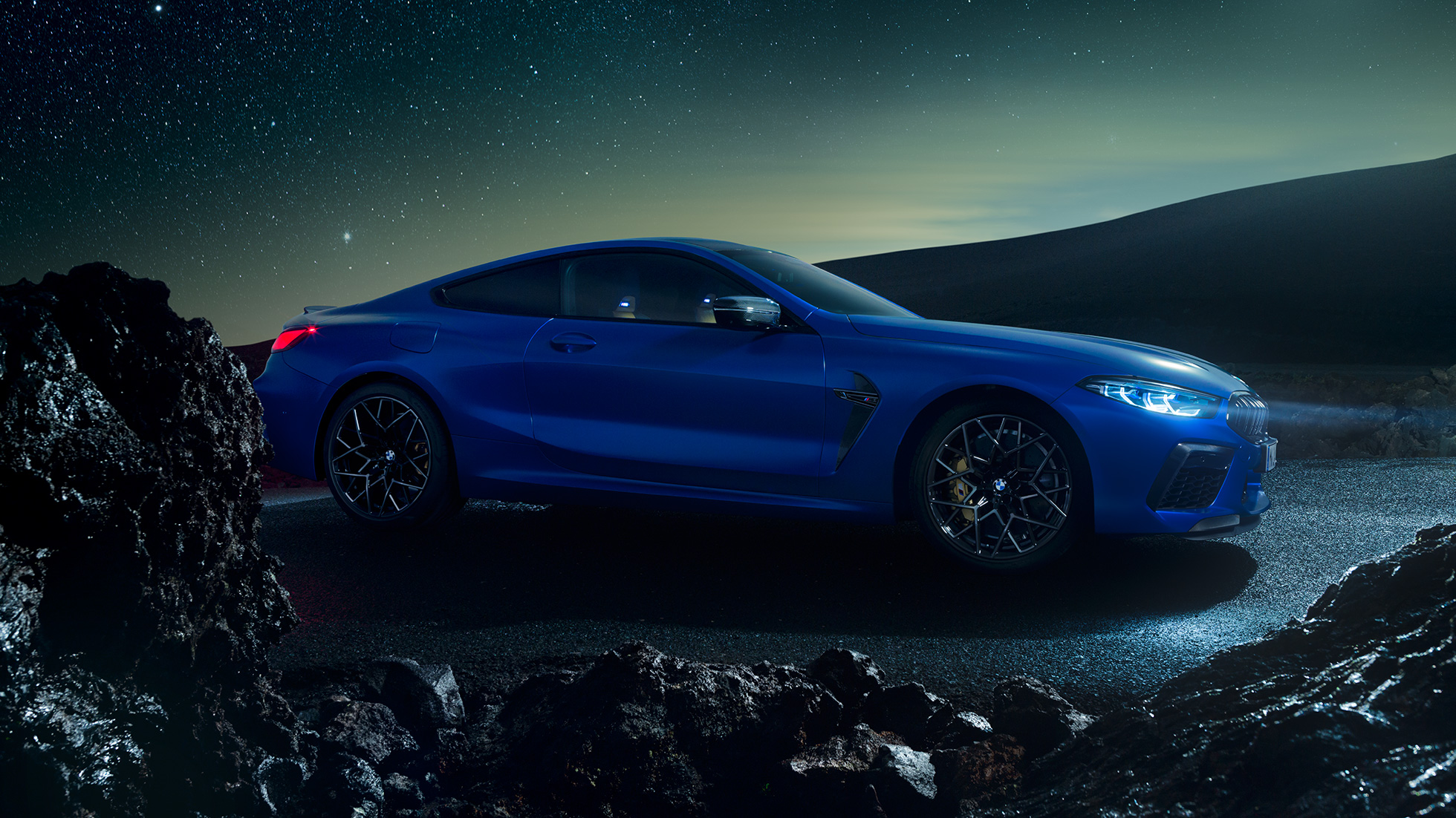 BMW M8 Competition Coupé, vista de tres cuartos del lateral. BMW M8 Competition Coupé en Marina Bay Blau metalizado, vista de tres cuartos del lateral, de noche.