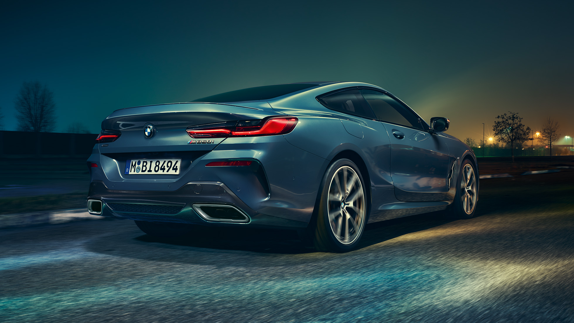 BMW M850i xDrive Coupé, vista de la zaga. BMW M850i xDrive Coupé en Barcelona Blau metalizado, vista de la zaga, en marcha, por la noche.