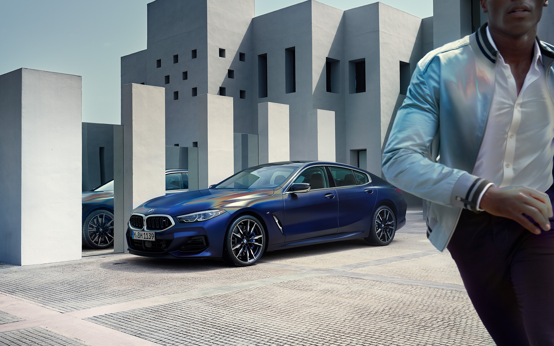 Vista de tres cuartos del frontal BMW M850i xDrive Gran Coupé G16 LCI Renovación 2022 BMW M850i xDrive Gran Coupé G16 LCI Renovación 2022 BMW Individual Frozen Tanzanite Blue metalizado, vista de tres cuartos del frontal, parado, con modelo masculino en primer plano