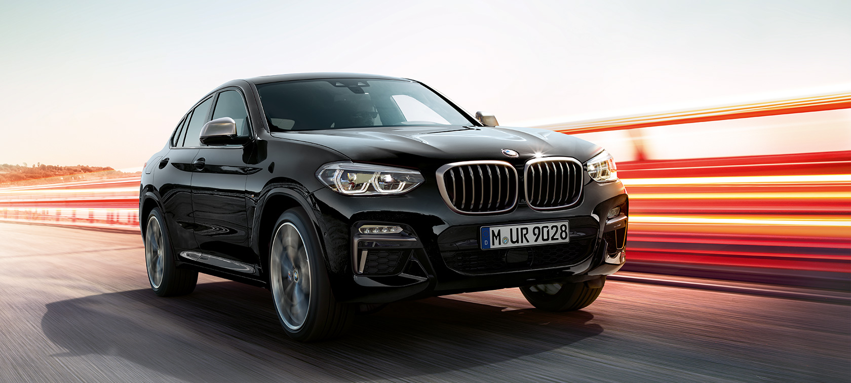 BMW X4 M40i y BMW X4 M40d, vista de tres cuartos del frontal, lado izquierdo BMW X4 M40i y BMW X4 M40d en Black Sapphire metalizado, exterior, vista de tres cuartos del frontal, lado izquierdo, bandas luminosas