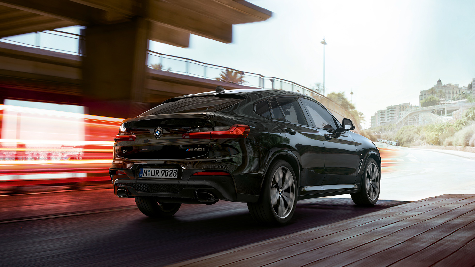 BMW X4 M40i, vista de tres cuartos del frontal BMW X4 M40i en Black Sapphire metalizado, conducción, exterior, vista de tres cuartos del frontal con bandas luminosas.