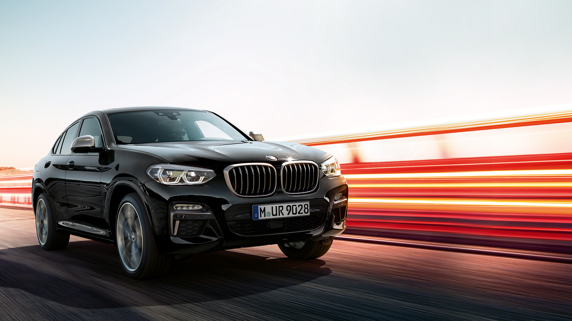 BMW X4 M40i, vista de tres cuartos de la zaga BMW X4 M40i en Black Sapphire metalizado, conducción, exterior, vista de tres cuartos de la zaga con bandas luminosas