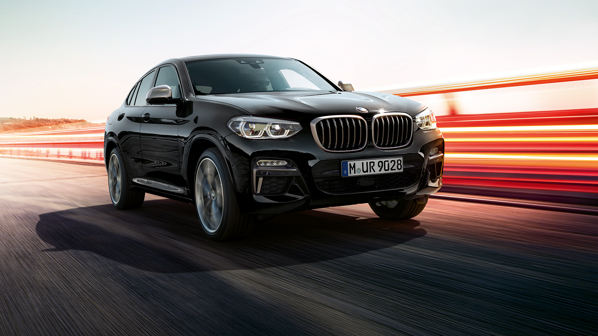 BMW X4 M40i y BMW X4 M40d, vista de tres cuartos del frontal BMW X4 M40i y BMW X4 M40d en Black Sapphire metalizado, exterior, vista de tres cuartos del frontal, lado izquierdo con bandas luminosas