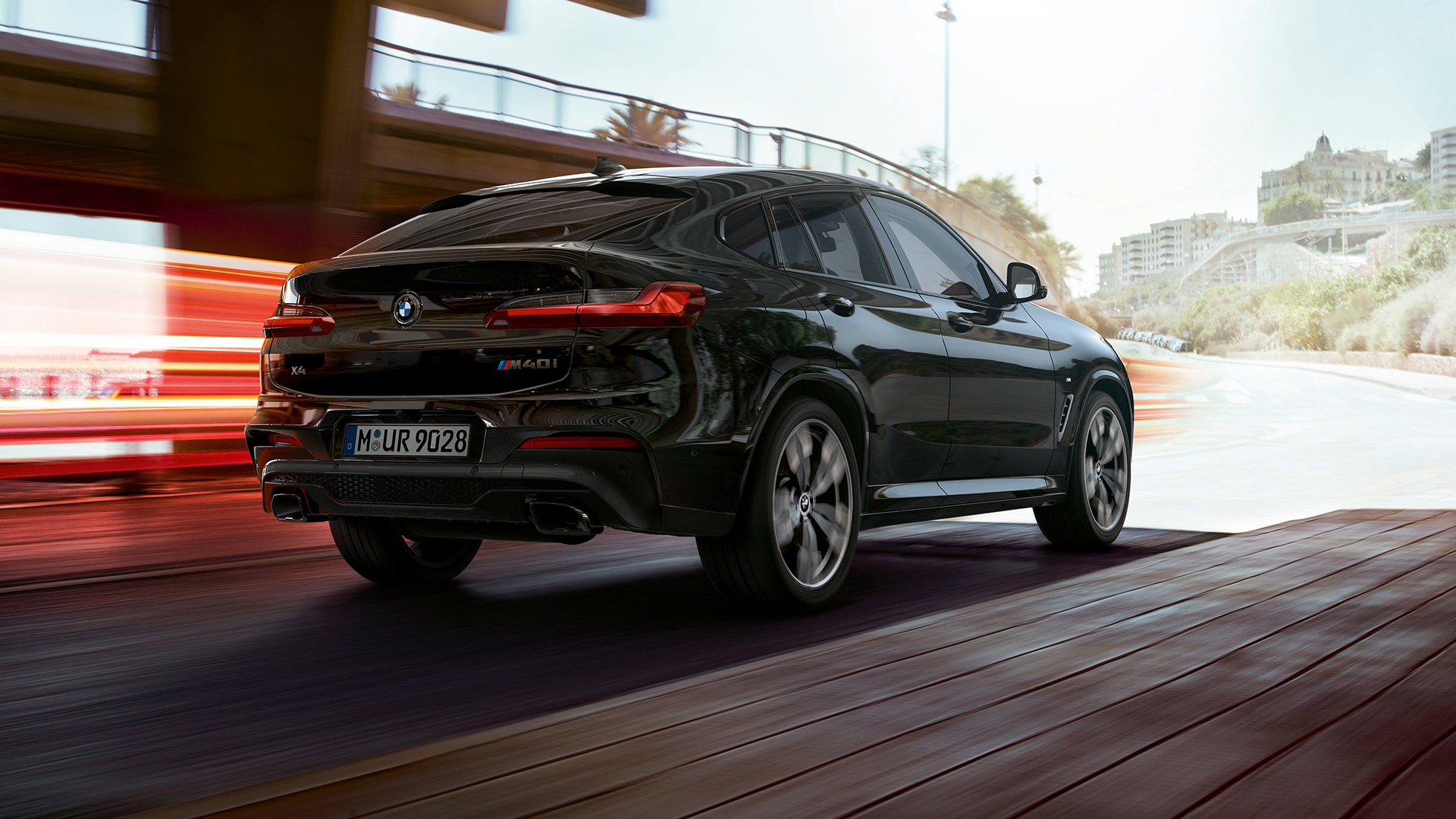 BMW X4 M40i, vista de tres cuartos de la zaga BMW X4 M40i en Black Sapphire metalizado, exterior, vista de tres cuartos de la zaga, lado derecho con bandas luminosas