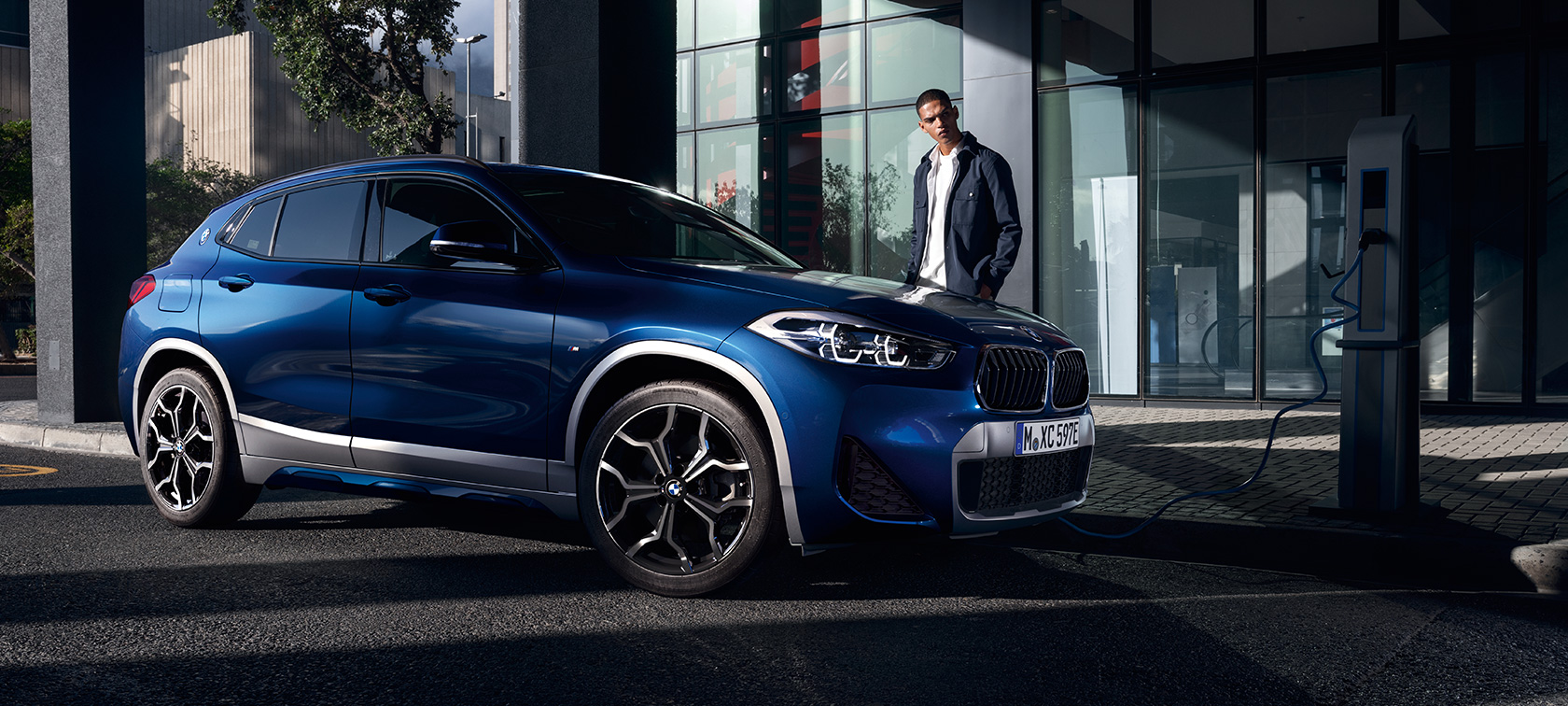 Híbrido enchufable BMW X2 xDrive25e SUV F39, vista de tres cuartos del lateral, en punto de carga Híbrido enchufable BMW X2 xDrive25e SUV F39, vista de tres cuartos del lateral, en punto de carga con modelo