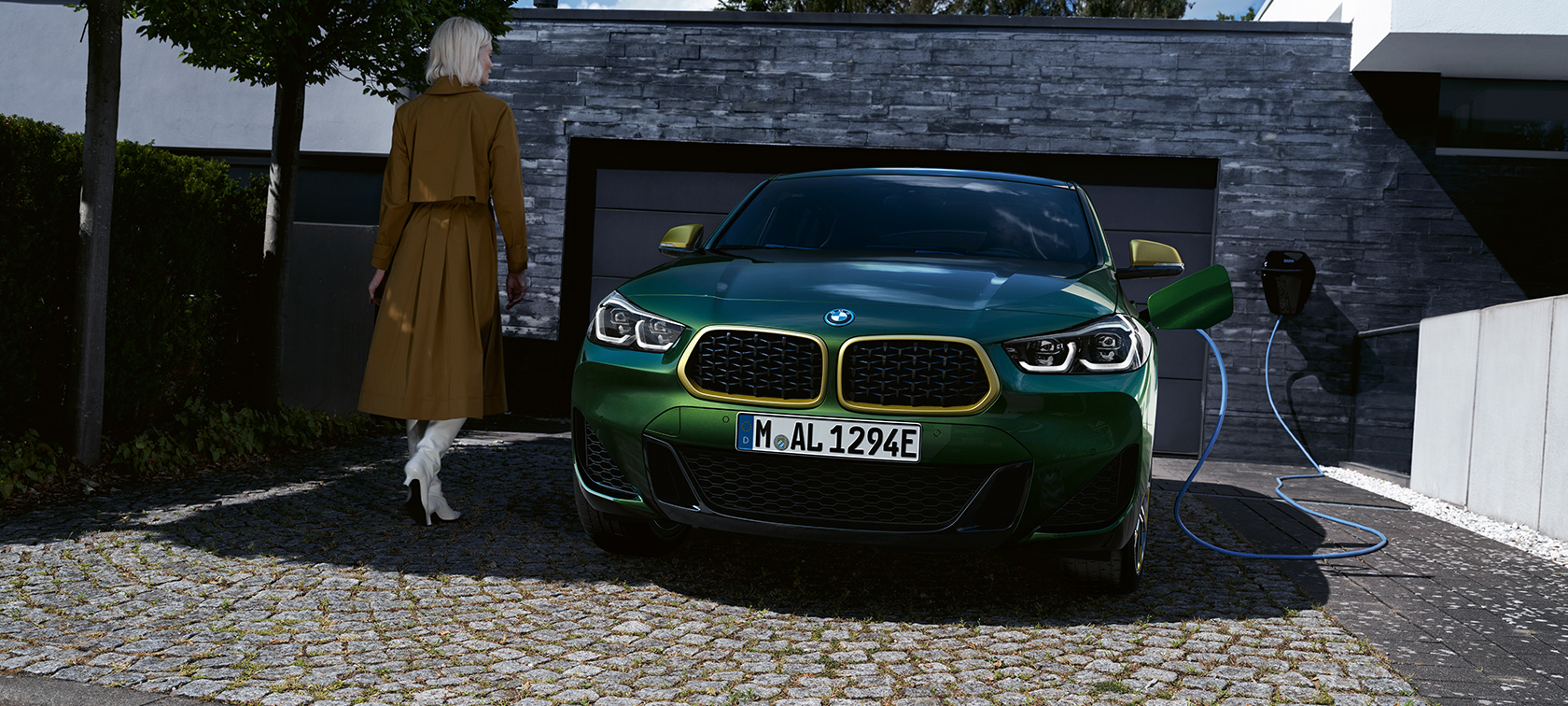 Vista del frontal BMW X2 F39 Sanremo Green metalizado Vista del frontal en situación de carga con modelo a la izquierda BMW X2 F39 Sanremo Green metalizado