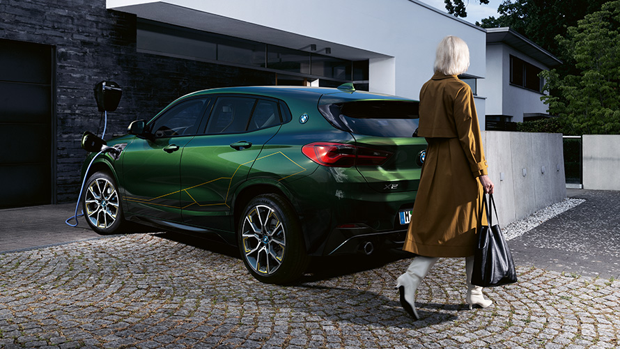 BMW X2 F39 Sanremo Green metalizado, vista de tres cuartos de la zaga, con modelo BMW X2 F39 Sanremo Green metalizado, vista de tres cuartos de la zaga, con modelo
