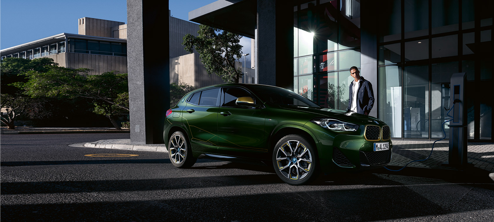 BMW X2 F39 Sanremo Green metalizado, vista de tres cuartos del lateral, con modelo BMW X2 F39 Sanremo Green metalizado, vista de tres cuartos del lateral, con modelo