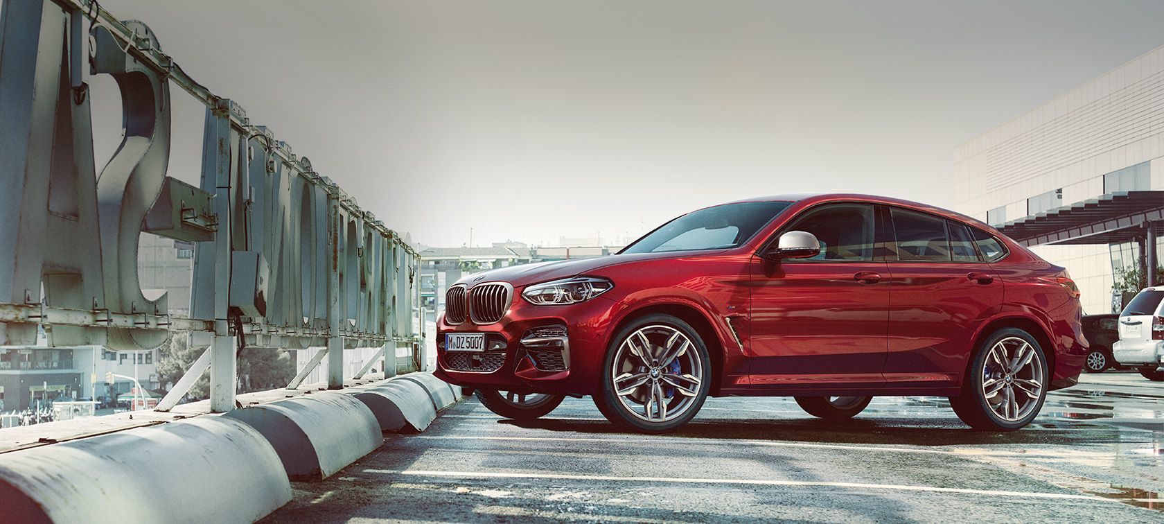 Aparcamiento, vista lateral BMW X4 SUV G02 BMW X4 M40i SUV G02 en color Flamencorot efecto brillante, vista lateral del SUV coupé