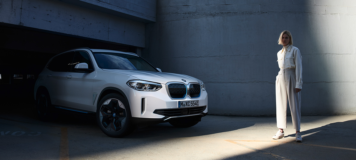 Mujer delante de BMW iX3 BMW iX3. Ahorra energía en tu SUV eléctrico.