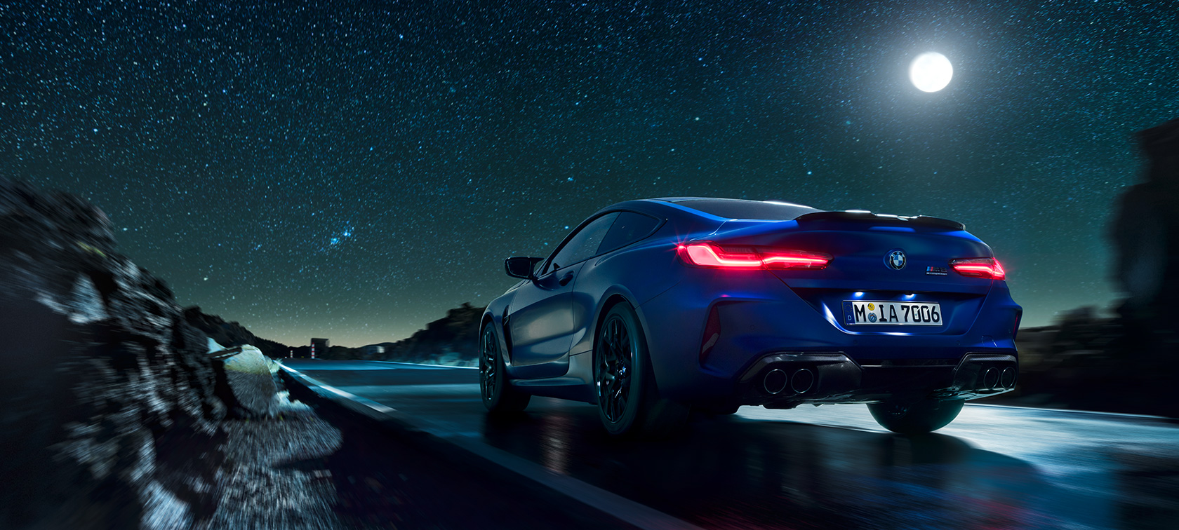 BMW M8 Competition Coupé, vista de la zaga. BMW M8 Competition Coupé, vista de la zaga, en marcha, por la noche con luna llena.