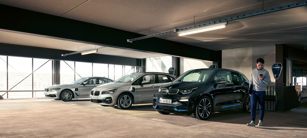 Vehículos BMW eléctricos e híbridos en un punto de carga Incentivos fiscales, vehículos BMW eléctricos e híbridos, hombre en un punto de carga