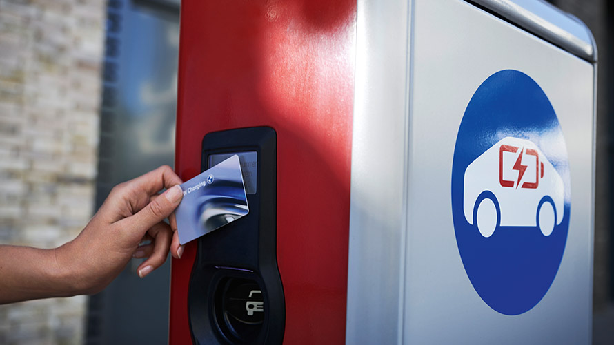 Carga pública con tarjeta BMW Charging Una persona sostiene una tarjeta BMW Charging en un punto de carga público