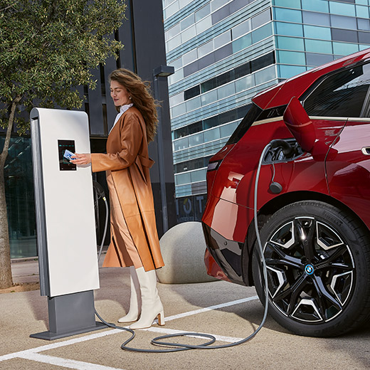 BMW iX i20 en punto de carga, mujer con tarjeta BMW Charging