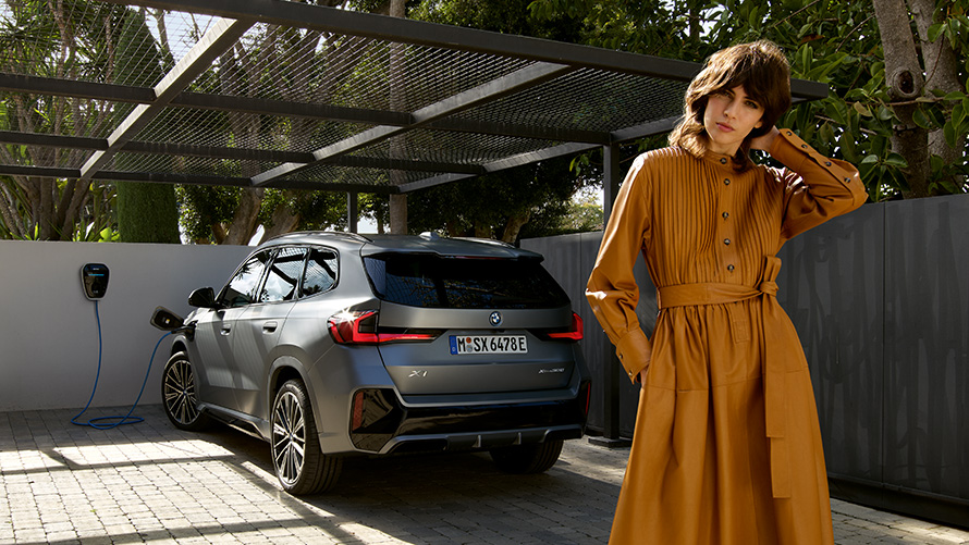 BMW X1 Híbrido Enchufable 2022 U11 vista de zaga, carga con modelo BMW X1 Híbrido Enchufable 2022 U11 vista de zaga, carga con modelo