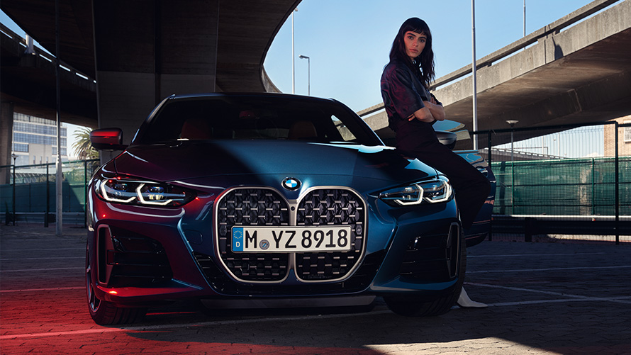 Una mujer se apoya en un BMW Serie 4 Coupé Remote Software Upgrade, una mujer se apoya en un BMW Serie 4 Coupé
