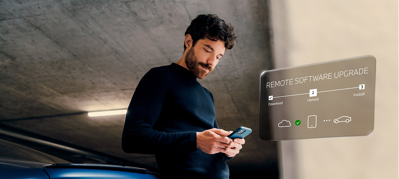Un hombre delante de un BMW mira su smartphone Remote Software Upgrade, un hombre delante de un BMW mira su smartphone