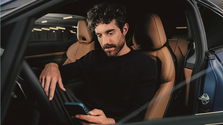 Hombre sentado en un BMW Hombre sentado en un BMW y mirando su smartphone