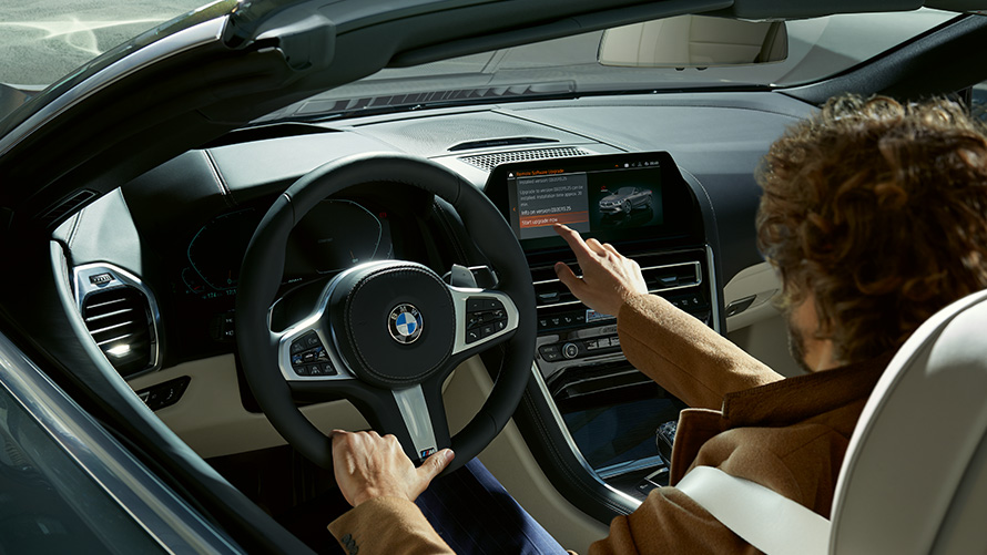 Remote Software Upgrade. Hombre sentado en un BMW utilizando el display de control Remote Software Upgrade Hombre sentado en un BMW utilizando el display de control